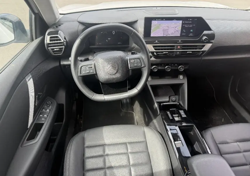 Vue intérieure frontale du poste de conduite de la Citroën C4 2025, avec volant multifonction et écran tactile central.