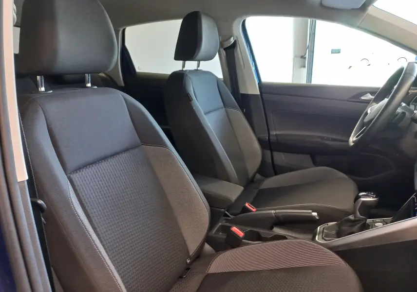 Vue intérieure côté droit du Volkswagen Taigo 2025 bleu récif, montrant les sièges avant en tissu noir et la console centrale.