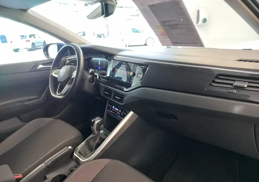 Vue intérieure côté conducteur du Volkswagen Taigo bleu récif 2025, avec tableau de bord numérique et console centrale moderne.