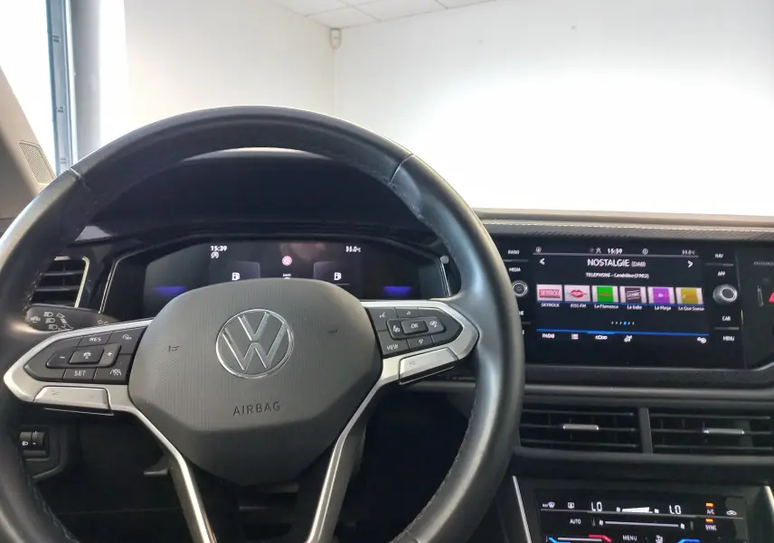 Vue intérieure centrée sur le volant Volkswagen et le tableau de bord numérique du Taigo 2025, avec écran tactile multimédia.