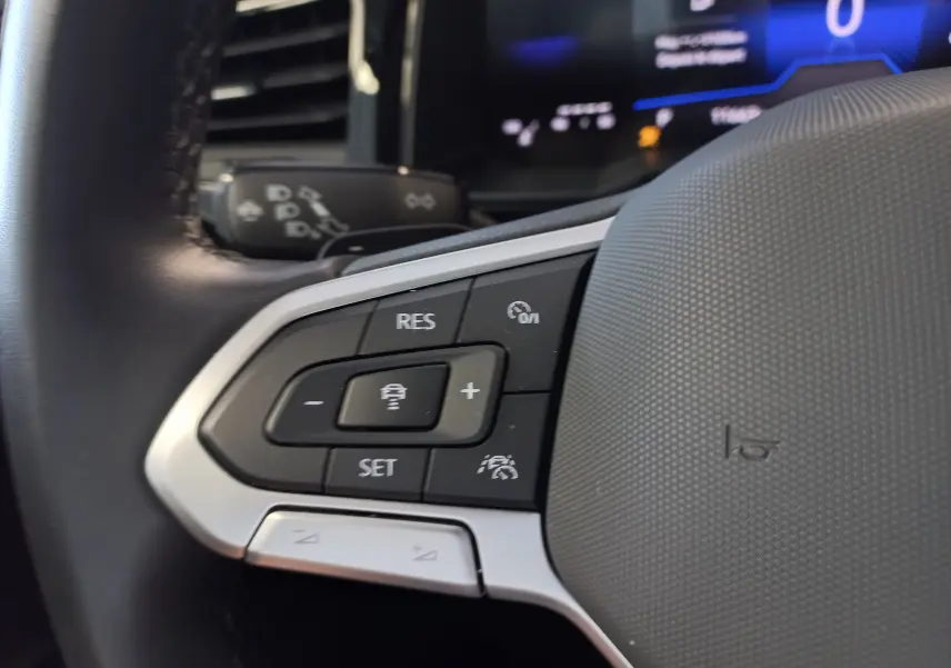 Gros plan sur les commandes de régulateur de vitesse au volant du Volkswagen Taigo bleu récif, version 2025.