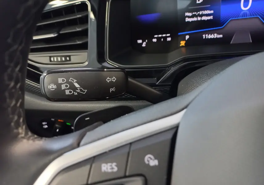 Gros plan sur la manette de clignotants et le tableau de bord numérique du Volkswagen Taigo 2025, intérieur noir.