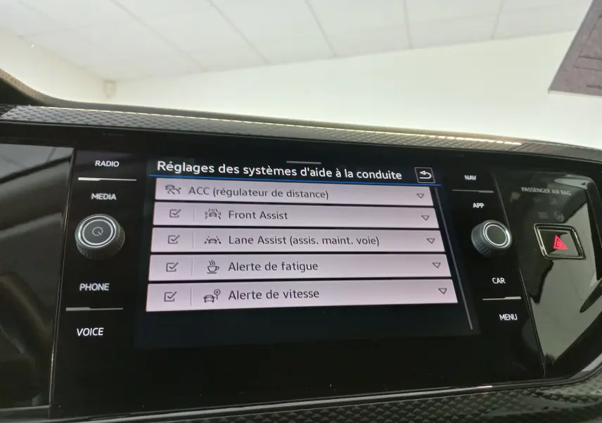 Écran tactile central du Volkswagen Taigo 2025 affichant les réglages des aides à la conduite, intérieur noir moderne.