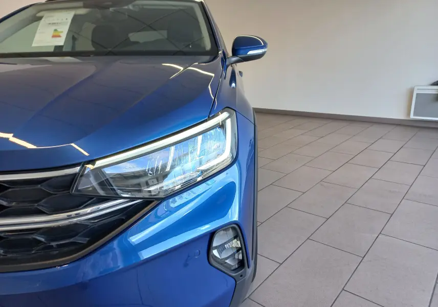 Gros plan sur l'avant droit du Volkswagen Taigo bleu récif, mettant en valeur le phare LED et la calandre noire.