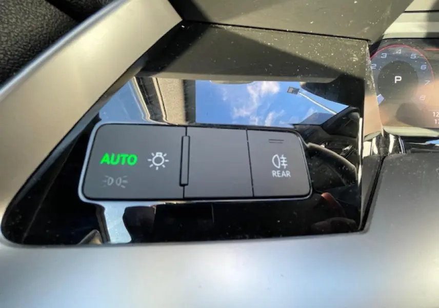 Gros plan sur les commandes d'éclairage avec mode auto activé dans l'habitacle de l'Audi A3 argent fleuret métal 2022.