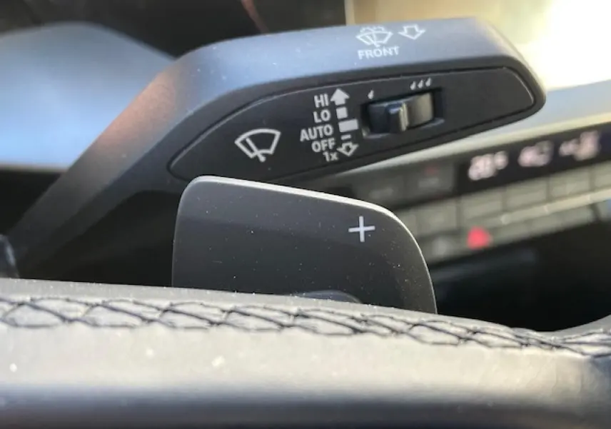 Gros plan sur la palette de changement de vitesses droite en cuir noir de l'Audi A3 2022, avec commandes d'essuie-glace en arrière-plan.