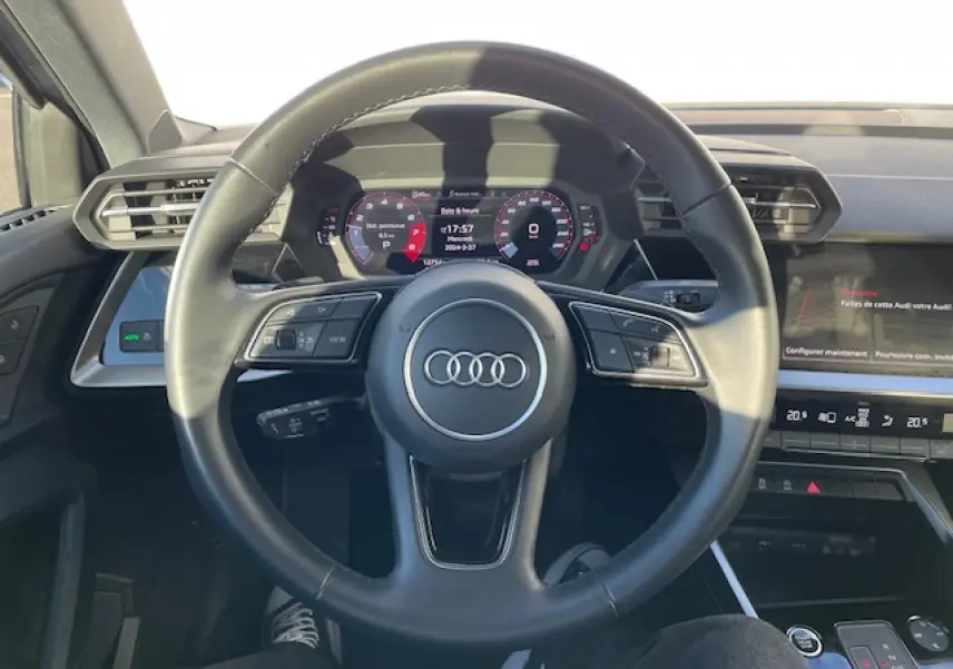 Vue centrée sur le volant cuir multifonctions de l'Audi A3 2022 avec tableau de bord digital et écran tactile.