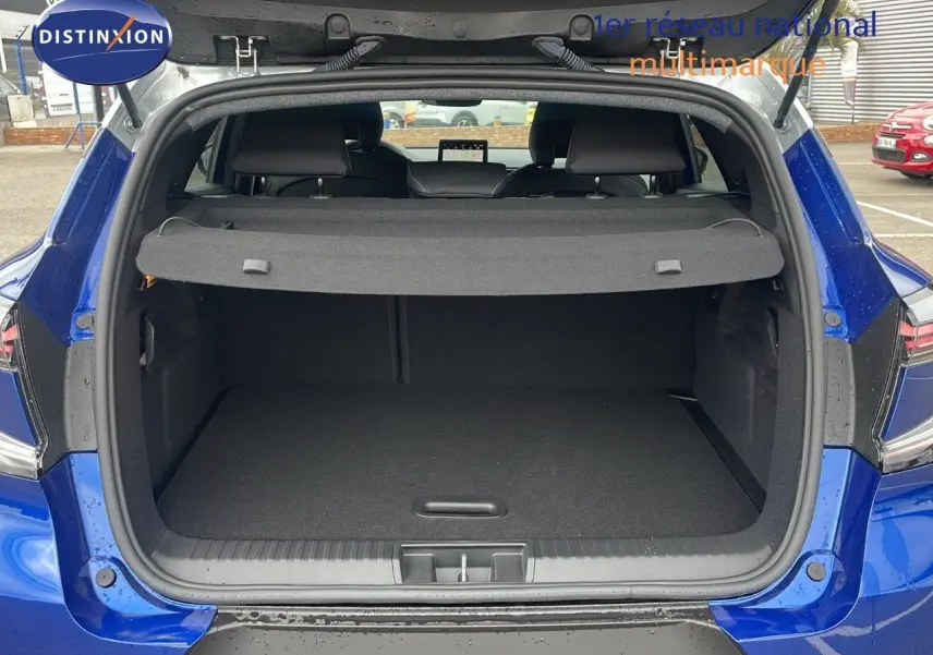 Coffre ouvert d'un Renault Captur E-Tech hybride 2025 bleu Iron Metal avec toit gris, vue arrière extérieure.