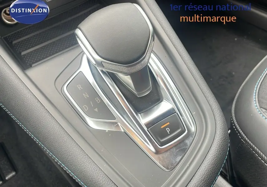 Le levier de vitesse automatique noir et chrome du Renault Captur E-Tech hybride 2025 avec surpiqûres bleues visibles.