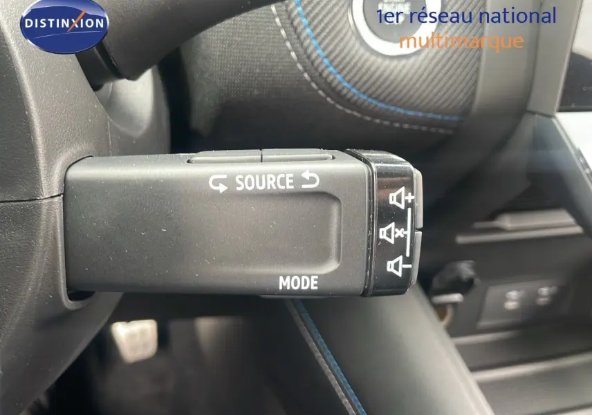 Gros plan sur la commande au volant du Renault Captur E-Tech hybride 2025 avec surpiqûres bleues et bouton Start visible.