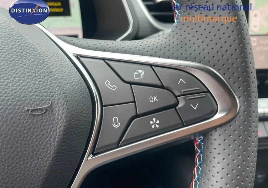Gros plan sur les commandes multifonctions à droite du volant perforé d'un Renault Captur E-Tech hybride 2025.