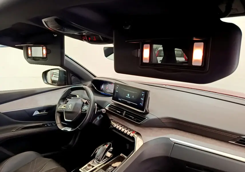 Intérieur du Peugeot 3008 GT 2021 rouge, vue côté conducteur, volant cuir et écran tactile central allumé.