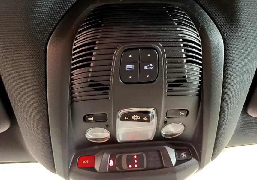Vue en gros plan du plafonnier intérieur du Peugeot 3008 GT rouge, avec commandes d'éclairage et bouton SOS rouge.