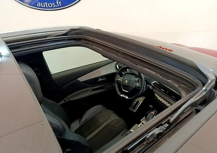 Vue plongeante sur l'intérieur noir du Peugeot 3008 GT 2021, avec volant cuir et tableau de bord moderne visible.