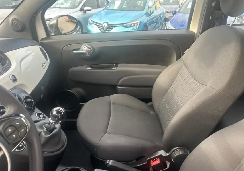 Intérieur côté passager du Fiat 500 blanc 2023, avec levier de vitesses manuel visible côté conducteur.