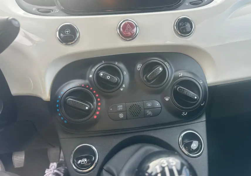 Gros plan sur la console centrale blanche et noire de la Fiat 500 blanche 2023, avec commandes de climatisation et levier de vitesse manuel.