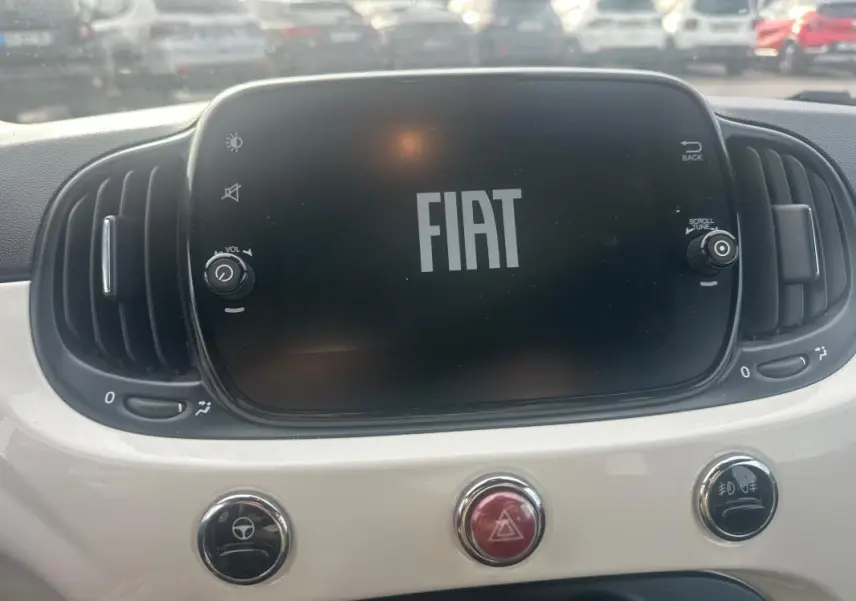 Écran central FIAT allumé avec logo, entouré de commandes et tableau de bord blanc d'une Fiat 500 2023.