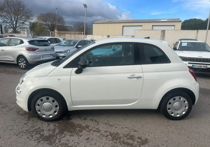 Profil côté gauche d'une FIAT 500 blanche de 2023, compacte et arrondie, avec jantes acier et rétroviseurs noirs.