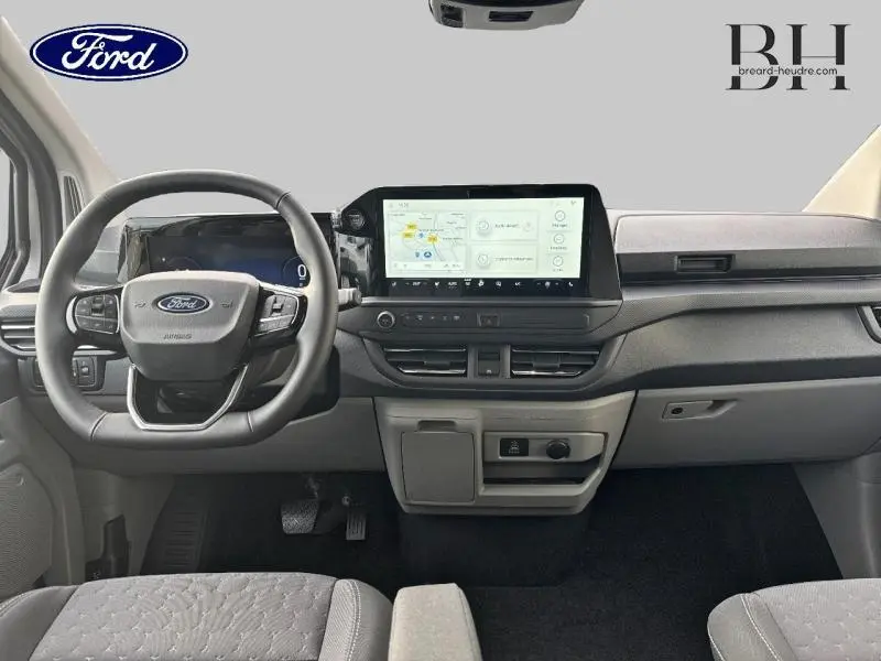 Vue intérieure avant du Ford Transit Custom Fourgon 2026, tableau de bord moderne avec écran tactile central et volant multifonctions.