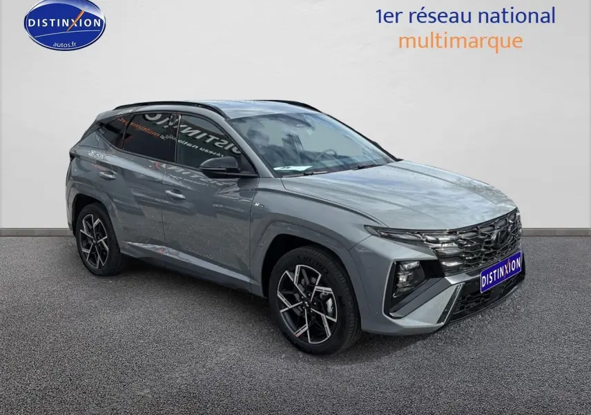 Vue 3/4 avant du Hyundai Tucson 2026 gris Shadow avec calandre noire brillante et jantes alliage 19 pouces.