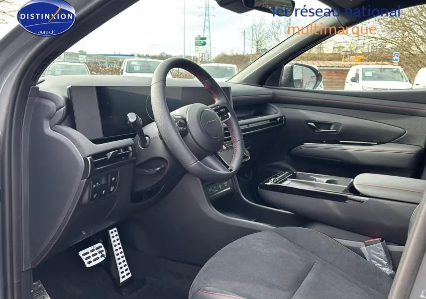 Intérieur côté conducteur du Hyundai Tucson 2026 gris shadow, volant cuir avec surpiqûres rouges et tableau de bord numérique.