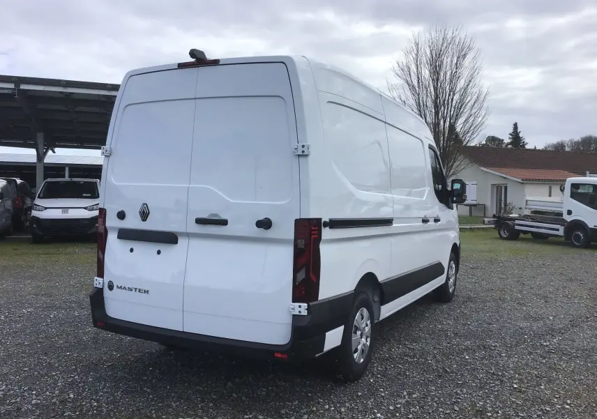 Vue 3/4 arrière droite d’un Renault Master blanc, fourgon utilitaire avec portes arrière fermées et détails noirs contrastants.
