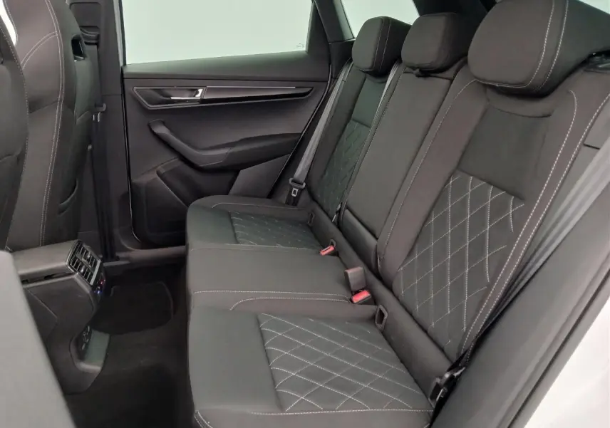 Vue intérieure côté droit des sièges arrière noirs avec surpiqûres blanches du Skoda Karoq 1.5 TSI 150 DSG7 Sportline 2025 blanc lune.