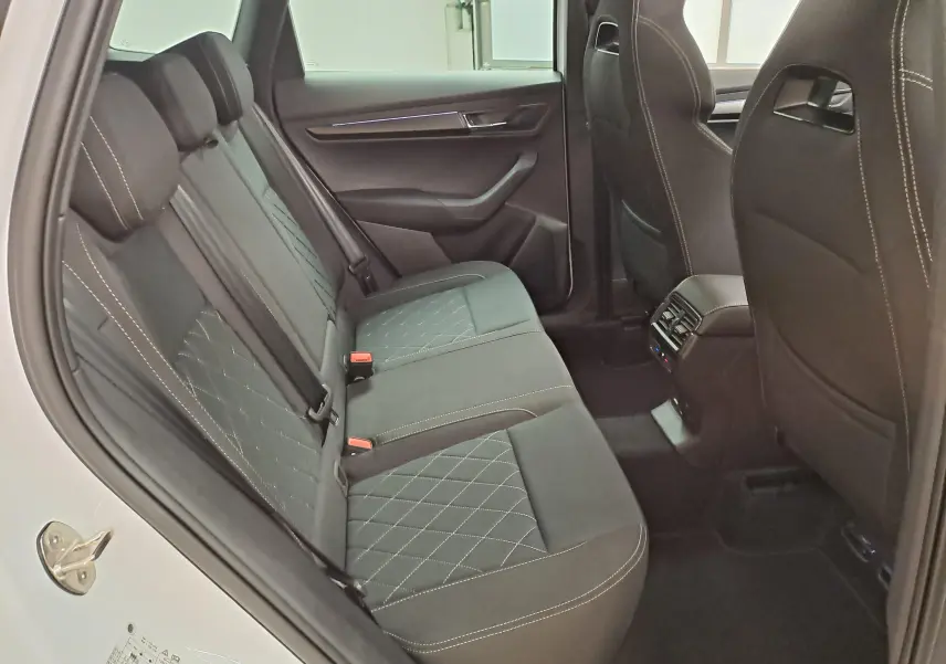 Vue intérieure côté gauche des sièges arrière noirs avec surpiqûres blanches du Skoda Karoq Blanc Lune 2025 Sportline.