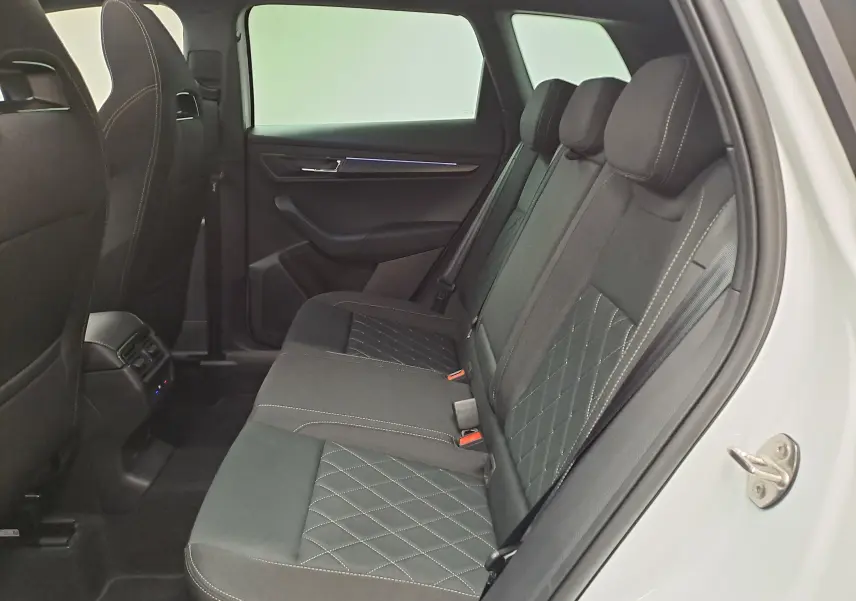 Vue intérieure côté gauche des sièges arrière noirs avec surpiqûres blanches du Skoda Karoq Blanc Lune 2025 version Sportline.