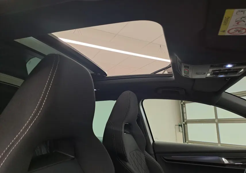Vue intérieure du toit ouvrant panoramique et des sièges sport noirs du Skoda Karoq 2025 Blanc Lune version Sportline.