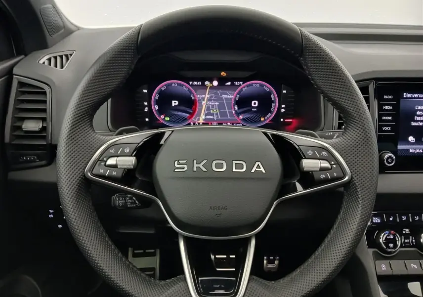 Vue intérieure centrée sur le volant perforé du Skoda Karoq 2025 avec tableau de bord numérique et commandes intégrées.