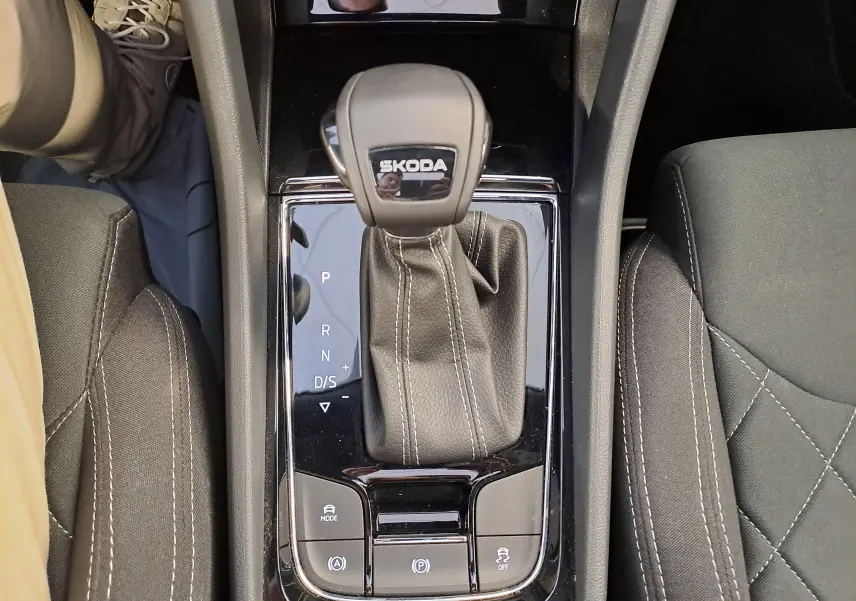 Vue plongeante sur la console centrale du Skoda Karoq 2025 blanc lune, mettant en valeur le levier de vitesse automatique et les sièges noirs.