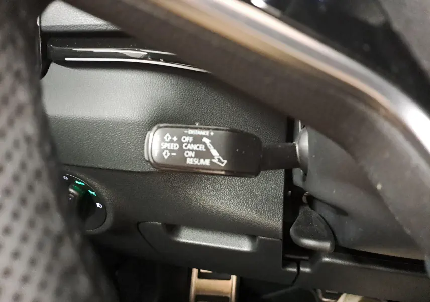 Gros plan sur la commande de régulateur de vitesse du Skoda Karoq 1.5 TSI blanc lune, côté gauche du volant.