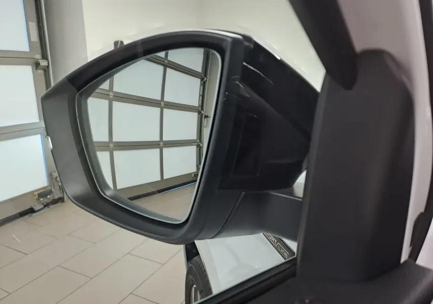 Rétroviseur extérieur côté gauche du Skoda Karoq 1.5 TSI 150 DSG7 Sportline blanc lune, avec logo Sportline visible sur la portière.