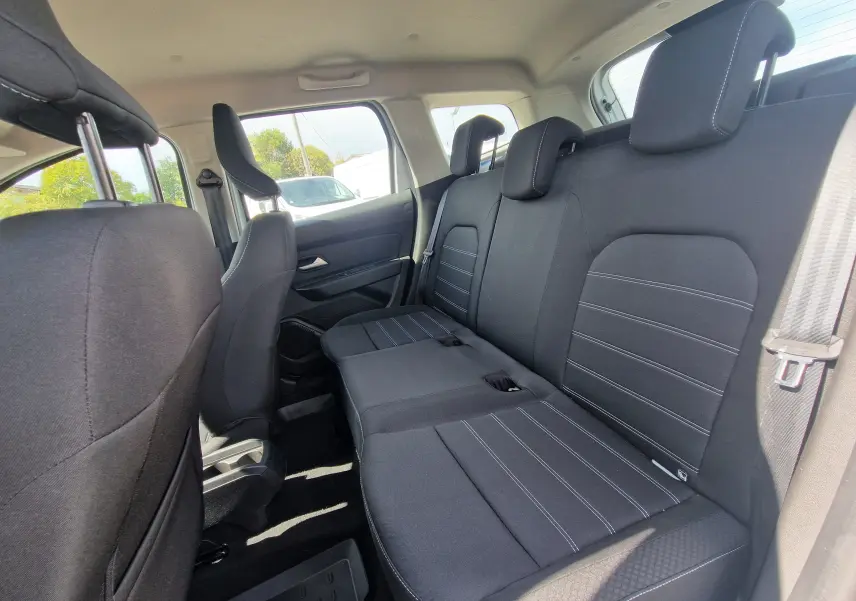 Vue intérieure côté droit montrant la banquette arrière noire du Dacia Duster 4x4 blanc, avec appuie-têtes et ceinture de sécurité.