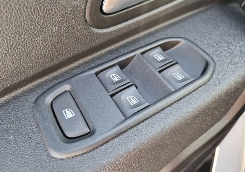 Gros plan sur les commandes des vitres électriques côté conducteur du Dacia Duster blanc 2023, finition Expression.