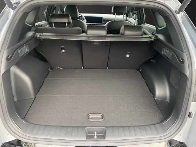 Vue arrière du coffre ouvert du Hyundai Tucson 1.6 Hybrid gris foncé, avec hayon motorisé et cache-bagages déployé.
