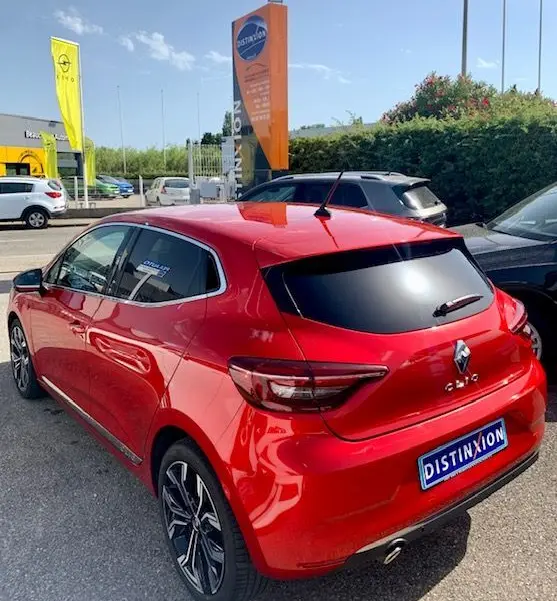 Vue 3/4 arrière droite d'une Renault Clio V rouge 2021 avec vitres teintées et jantes alliage distinctives