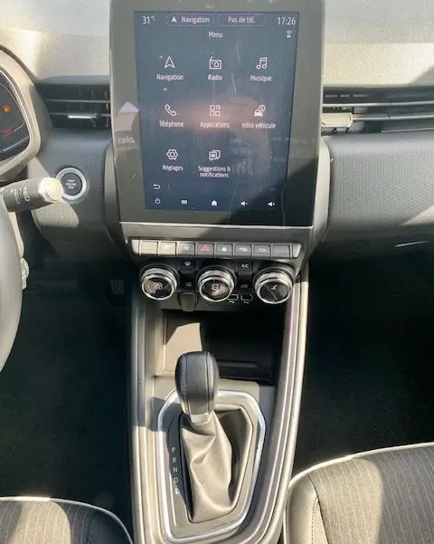 Vue rapprochée de la console centrale de la Renault Clio V rouge 2021, avec écran tactile et levier de boîte automatique.