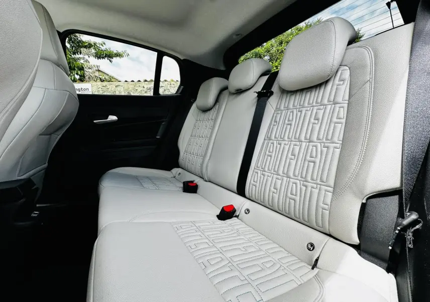 Vue intérieure côté droit des sièges arrière ivoire soft touch avec monogrammes FIAT embossés sur la Fiat 600 hybride 2024.