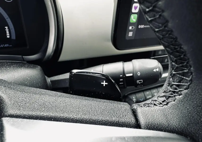 Gros plan sur la palette de changement de rapports côté droit du volant de la Fiat 600 La Prima bleu clair, tableau de bord partiel visible.