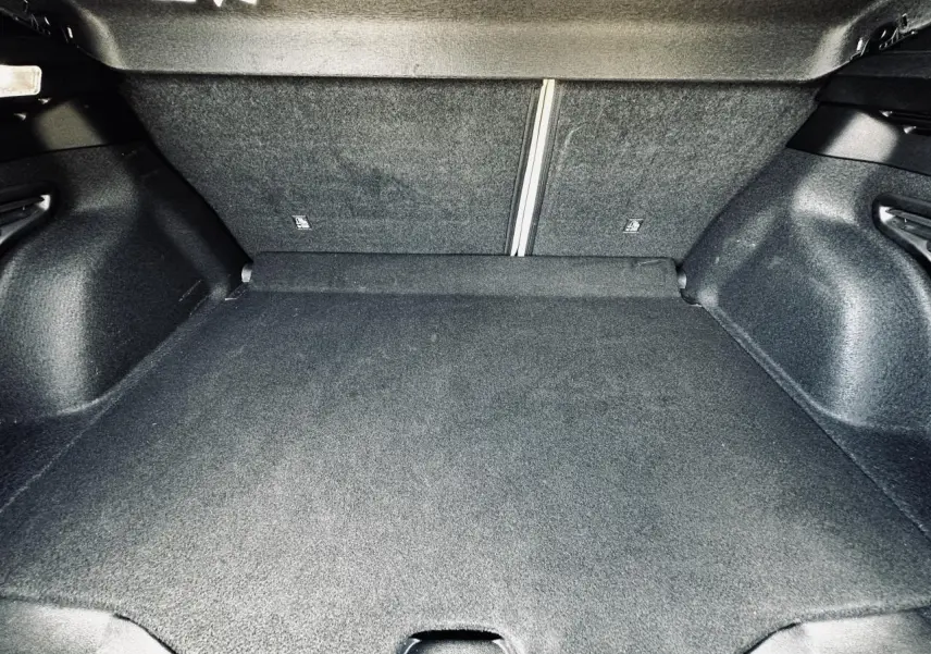 Coffre spacieux de la FIAT 600 1.2 Hybrid La Prima 2024, vue intérieure avec banquette arrière rabattue, revêtement noir.