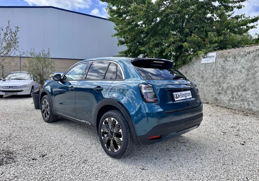 Vue 3/4 arrière droite d'une FIAT 600 hybride bleu clair avec feux arrière à LED et jantes stylisées.