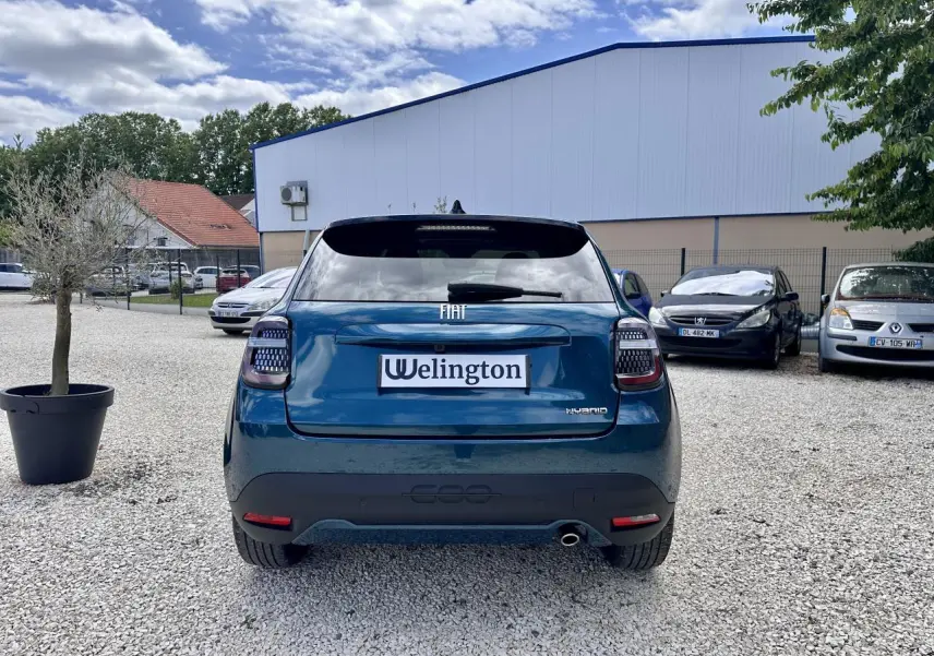 Vue arrière d'une FIAT 600 hybride bleu clair avec feux arrière LED et logo FIAT visible sur un parking.
