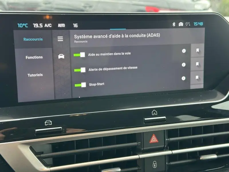 Écran tactile central affichant les aides à la conduite du Citroën C4 X 1.2 Hybride 145ch, intérieur moderne noir.