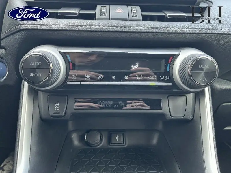 Vue frontale du tableau de bord du Toyota RAV4 noir, mettant en valeur les commandes de climatisation automatique bi-zone et les boutons multifonctions.