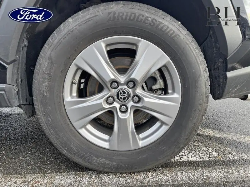 Gros plan sur la roue avant droite du Toyota RAV4 noir métallisé avec jante alliage et logo Toyota central.