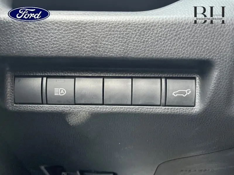Gros plan sur les boutons de commande intérieurs noirs du Toyota RAV4 2.5 Hybride 2022, dont ouverture coffre.