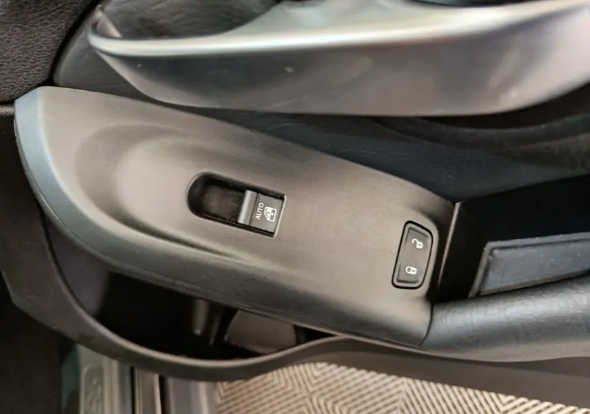 Gros plan sur la commande de lève-vitre et verrouillage de porte côté conducteur d'une FIAT 500X blanche.