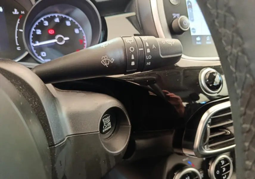 Gros plan intérieur sur le tableau de bord noir de la Fiat 500X, avec bouton start/stop et commande essuie-glace.